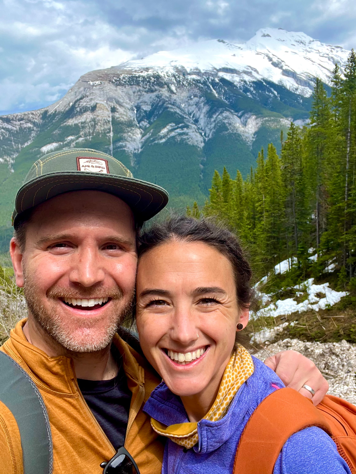 Matthew Oliver smiling with a loved one on a mountainside above snow-dusted pines
